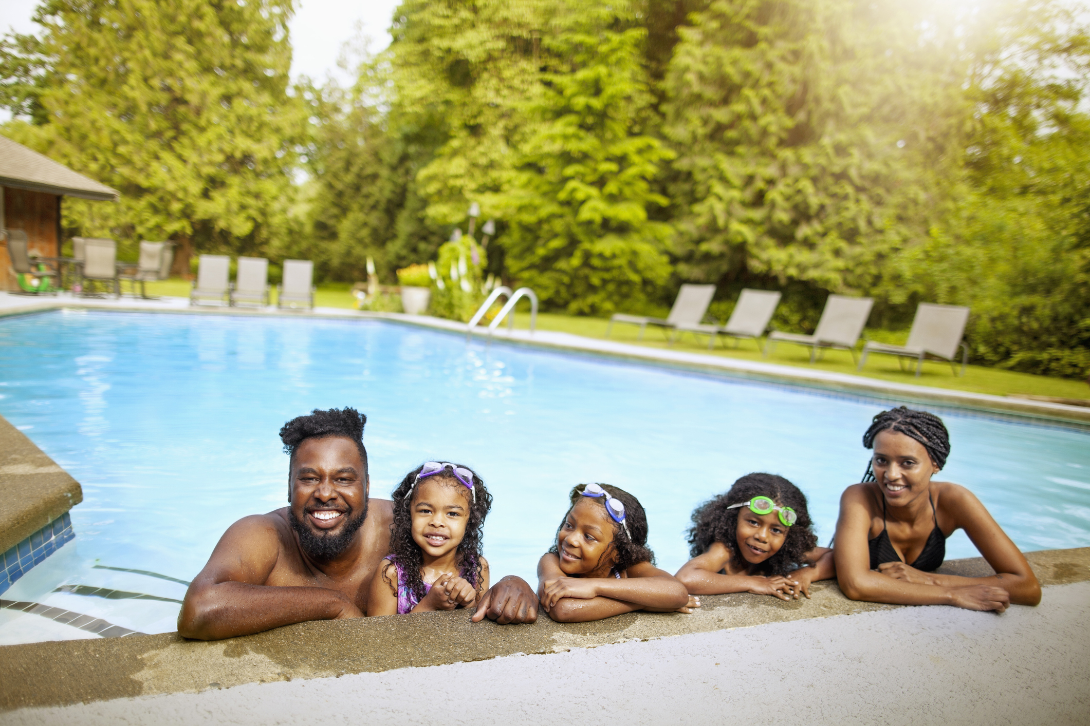 Family relaxing at the edge of a backyard swimming pool